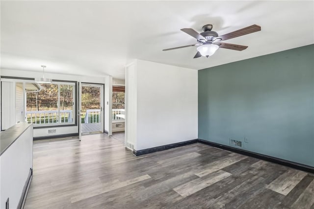 empty room with ceiling fan, a barn door, and dark wood-type flooring