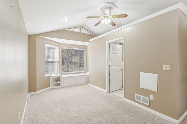 carpeted spare room featuring ceiling fan, crown molding, and vaulted ceiling