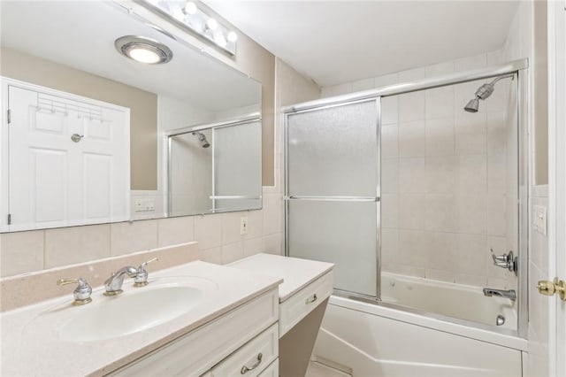 bathroom with combined bath / shower with glass door, vanity, tile walls, and backsplash