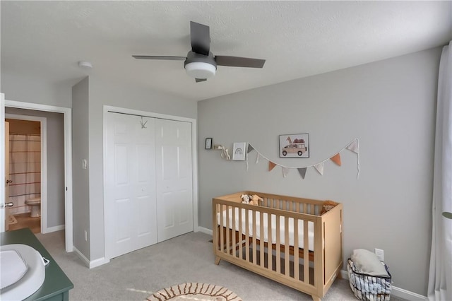 bedroom featuring ceiling fan, sink, light carpet, a closet, and a crib