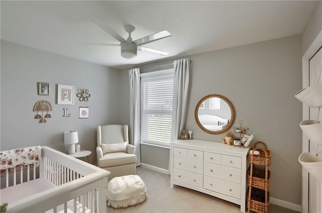 carpeted bedroom featuring ceiling fan and a nursery area