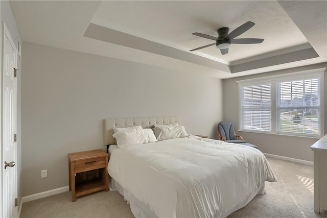 bedroom featuring ceiling fan, a raised ceiling, light carpet, and crown molding