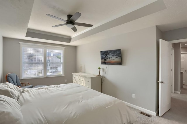 carpeted bedroom with a tray ceiling, ceiling fan, and ornamental molding