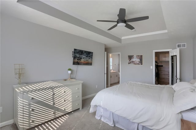 carpeted bedroom with ensuite bathroom, ceiling fan, a spacious closet, a tray ceiling, and a closet