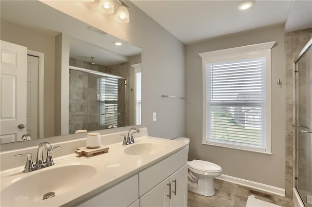 bathroom with vanity, toilet, and a shower with door