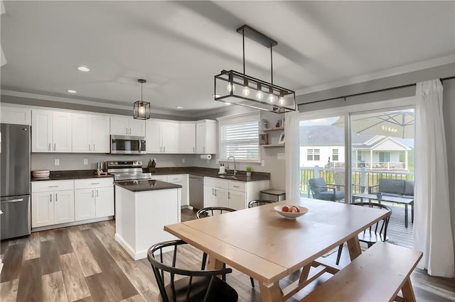 kitchen with pendant lighting, a center island, white cabinets, and stainless steel appliances