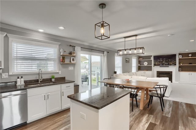 kitchen with a center island, sink, stainless steel dishwasher, decorative light fixtures, and white cabinetry