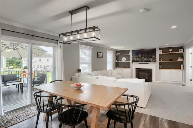 dining area with hardwood / wood-style floors, built in features, and crown molding