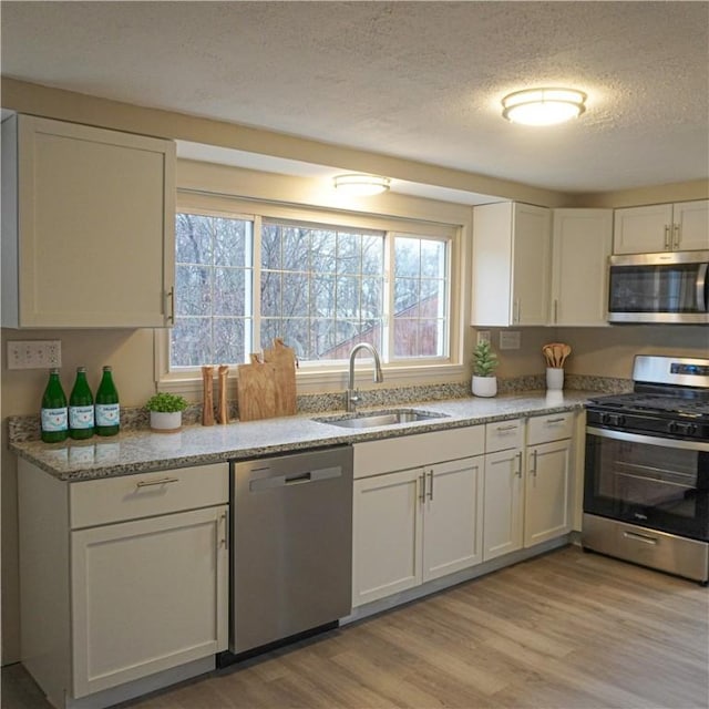 kitchen featuring white cabinets, stainless steel appliances, light hardwood / wood-style flooring, and sink