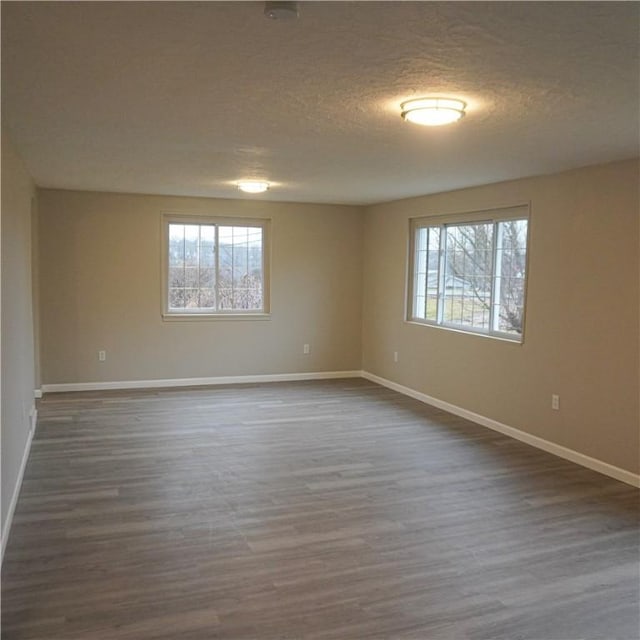 empty room featuring a textured ceiling and dark wood-type flooring