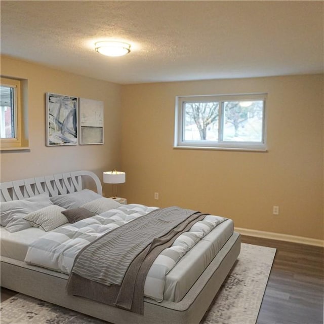 bedroom with a textured ceiling, dark hardwood / wood-style floors, and multiple windows