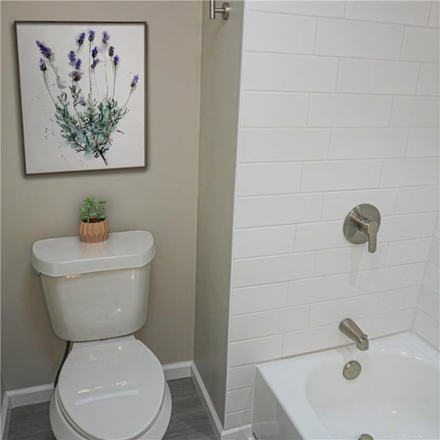 bathroom featuring washtub / shower combination, hardwood / wood-style flooring, and toilet