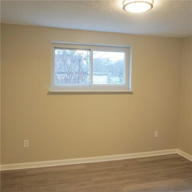 spare room featuring a wealth of natural light, a textured ceiling, and hardwood / wood-style flooring