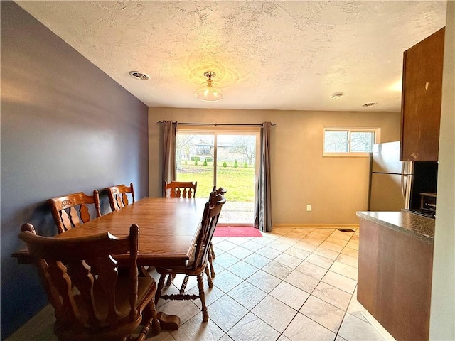 tiled dining room with a textured ceiling