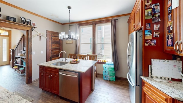 kitchen with a center island with sink, crown molding, sink, decorative light fixtures, and stainless steel appliances