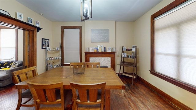 dining area featuring a fireplace, dark hardwood / wood-style flooring, and a notable chandelier