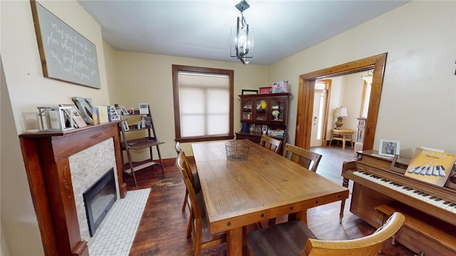 dining space with a notable chandelier, dark wood-type flooring, and a tile fireplace