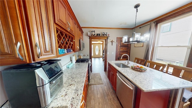 kitchen with a kitchen breakfast bar, stainless steel appliances, crown molding, sink, and decorative light fixtures