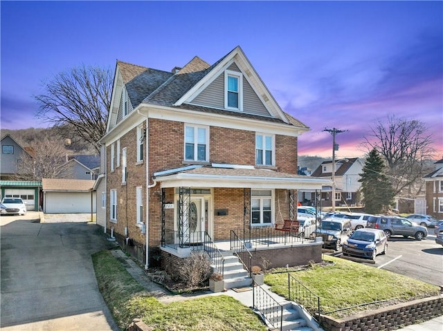 american foursquare style home with brick siding, roof with shingles, uncovered parking, and an outbuilding