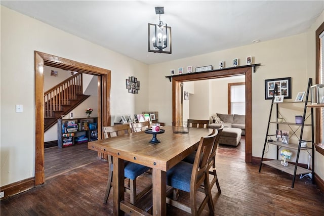 dining space with wood finished floors, baseboards, a notable chandelier, and stairs