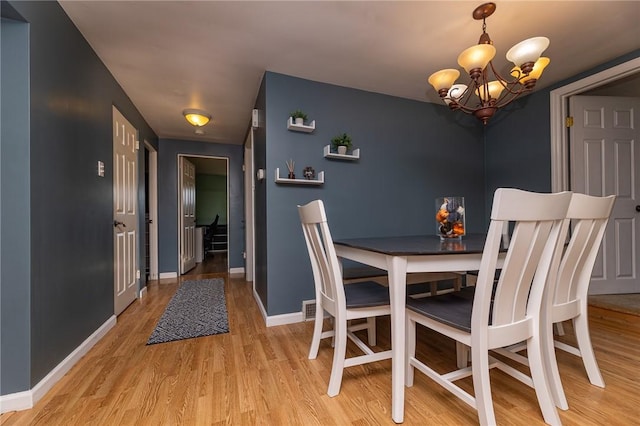 dining area featuring light hardwood / wood-style floors and an inviting chandelier