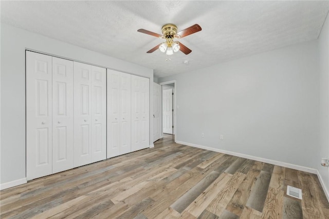 unfurnished bedroom featuring a textured ceiling, light hardwood / wood-style flooring, and ceiling fan