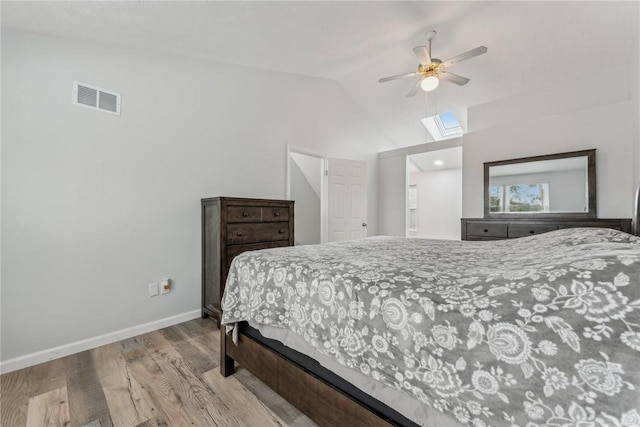 bedroom featuring ceiling fan, lofted ceiling with skylight, and light hardwood / wood-style flooring