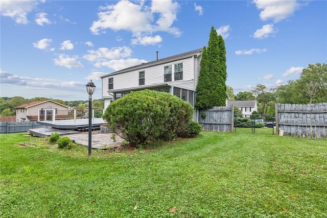 back of house featuring a yard, a patio, a sunroom, and a wooden deck