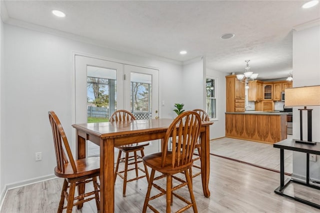 dining area with a notable chandelier, light wood-type flooring, and crown molding