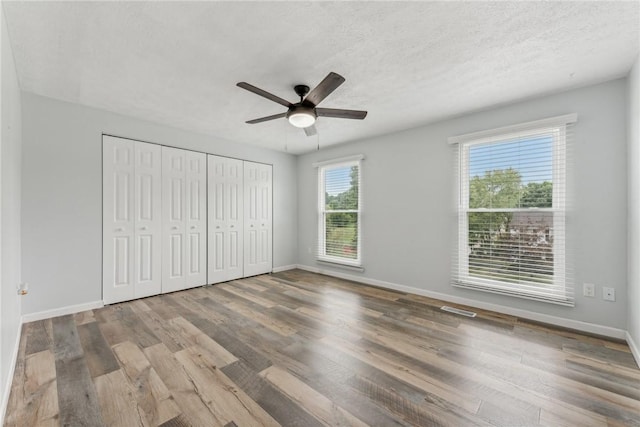 unfurnished bedroom with hardwood / wood-style flooring, ceiling fan, a textured ceiling, and a closet