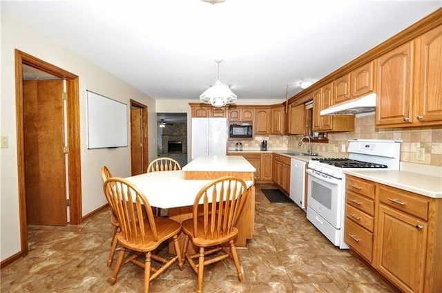 kitchen with backsplash, white appliances, sink, a kitchen island, and hanging light fixtures