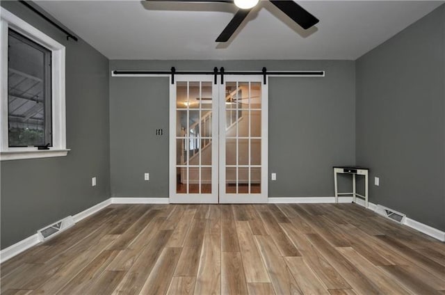 unfurnished room featuring a barn door, ceiling fan, and hardwood / wood-style flooring