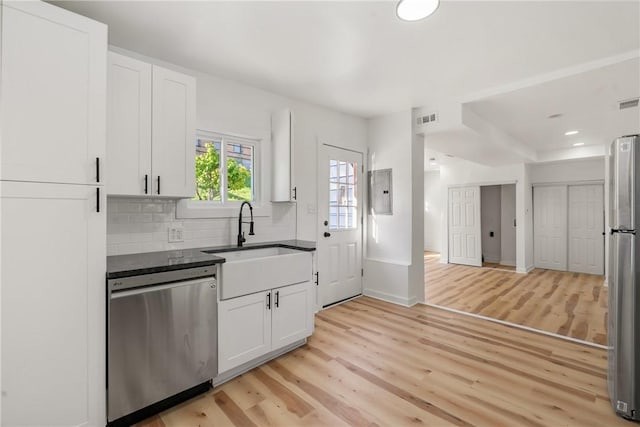 kitchen featuring sink, light hardwood / wood-style flooring, appliances with stainless steel finishes, tasteful backsplash, and white cabinetry