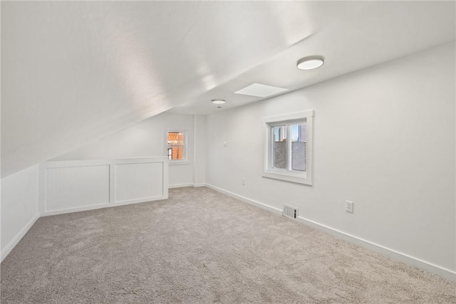 carpeted empty room with vaulted ceiling