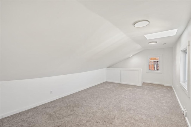 bonus room featuring light carpet and vaulted ceiling with skylight