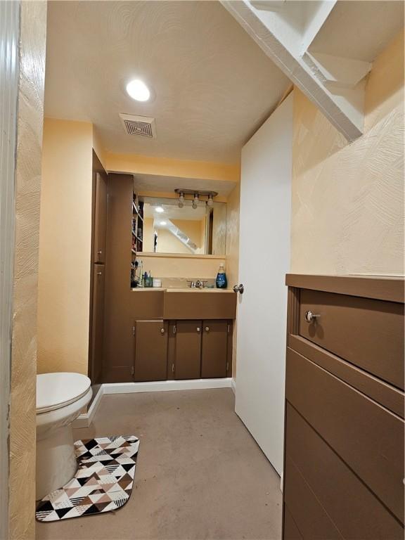 bathroom featuring vanity, concrete floors, and toilet