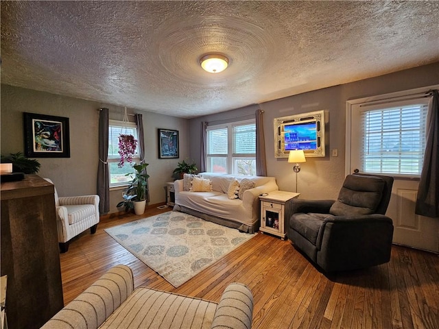 living room featuring a wealth of natural light, wood-type flooring, and a textured ceiling