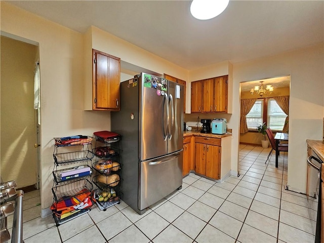 kitchen featuring stainless steel refrigerator, light tile patterned flooring, and an inviting chandelier