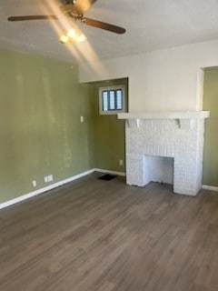 unfurnished living room with a fireplace, dark hardwood / wood-style flooring, and ceiling fan