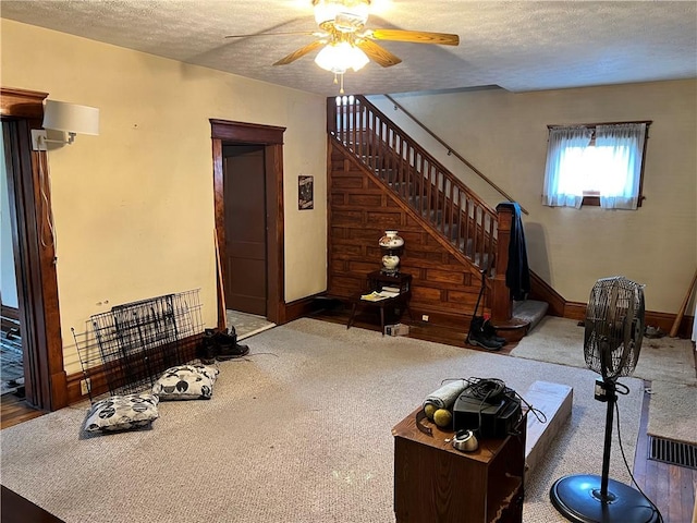 living room featuring carpet flooring, ceiling fan, and a textured ceiling