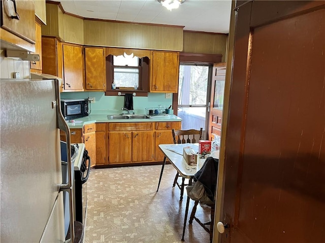 kitchen featuring wood walls, stove, white fridge, and sink