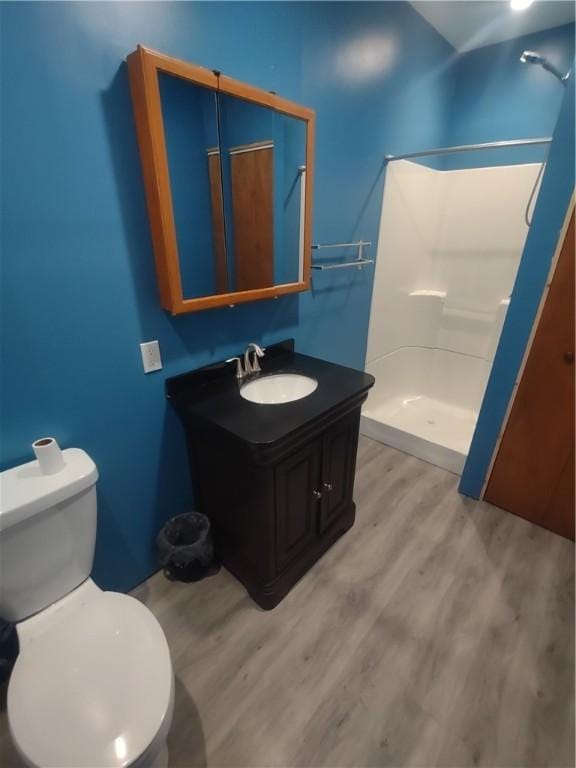 bathroom with a shower, hardwood / wood-style floors, vanity, and toilet