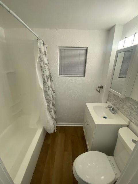 full bathroom with vanity, hardwood / wood-style floors, shower / bath combination with curtain, and toilet