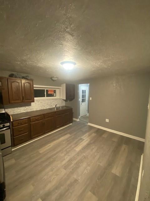 kitchen with sink, tasteful backsplash, a textured ceiling, white gas range, and hardwood / wood-style floors