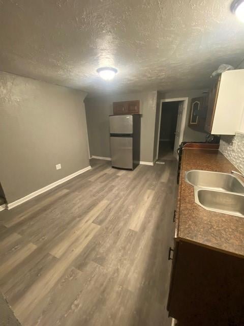 kitchen featuring sink, dark wood-type flooring, stainless steel refrigerator, and a textured ceiling