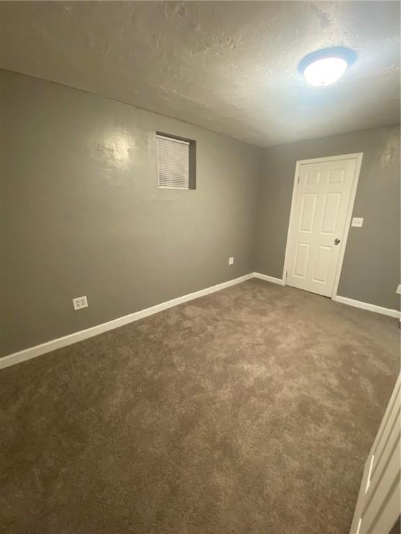 carpeted empty room featuring a textured ceiling