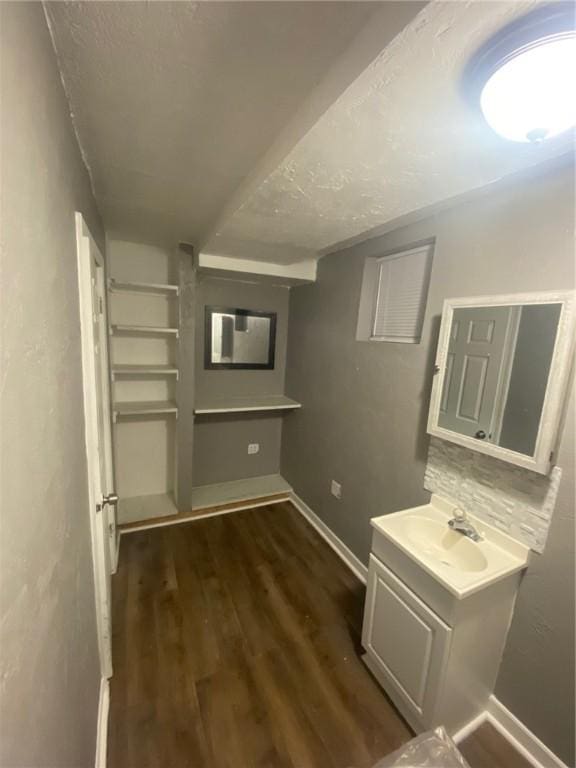 interior space featuring hardwood / wood-style flooring, vanity, a textured ceiling, and decorative backsplash