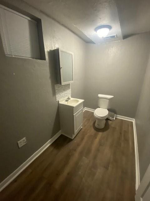 bathroom featuring vanity, hardwood / wood-style floors, tasteful backsplash, and toilet