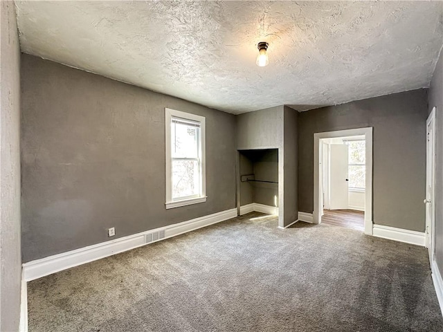 unfurnished bedroom with multiple windows, carpet floors, and a textured ceiling