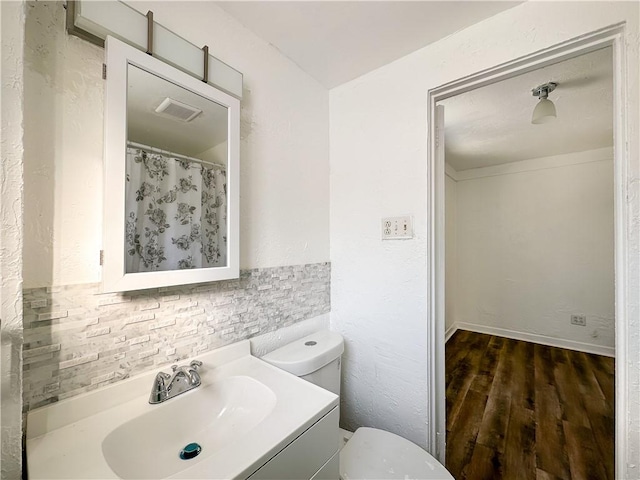 bathroom featuring vanity, hardwood / wood-style floors, decorative backsplash, and toilet